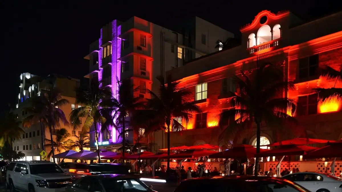 Real photo of Ocean Drive, Miami Beach, at night: art deco hotels with red and purple neon lights